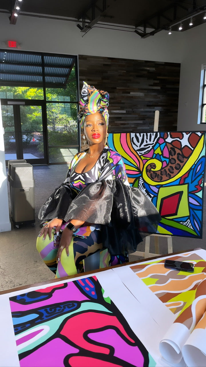 Melissa Mitchell sitting beside her high-quality art prints while wearing her collectible Wildfactor kimono, featuring original wearable art and designs available on MelissaAMitchell.com.